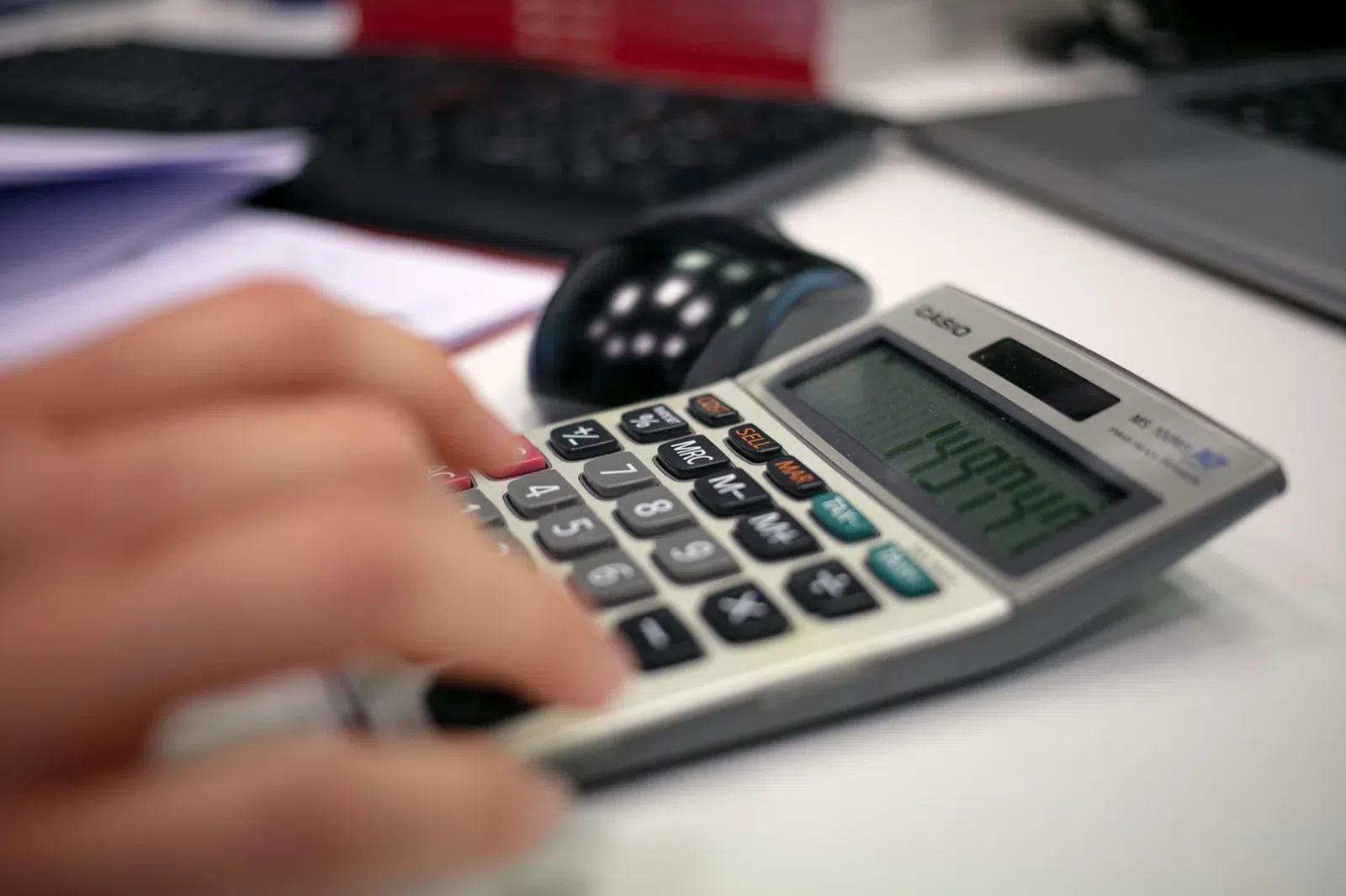 Persona calculando y revisando documentación financiera